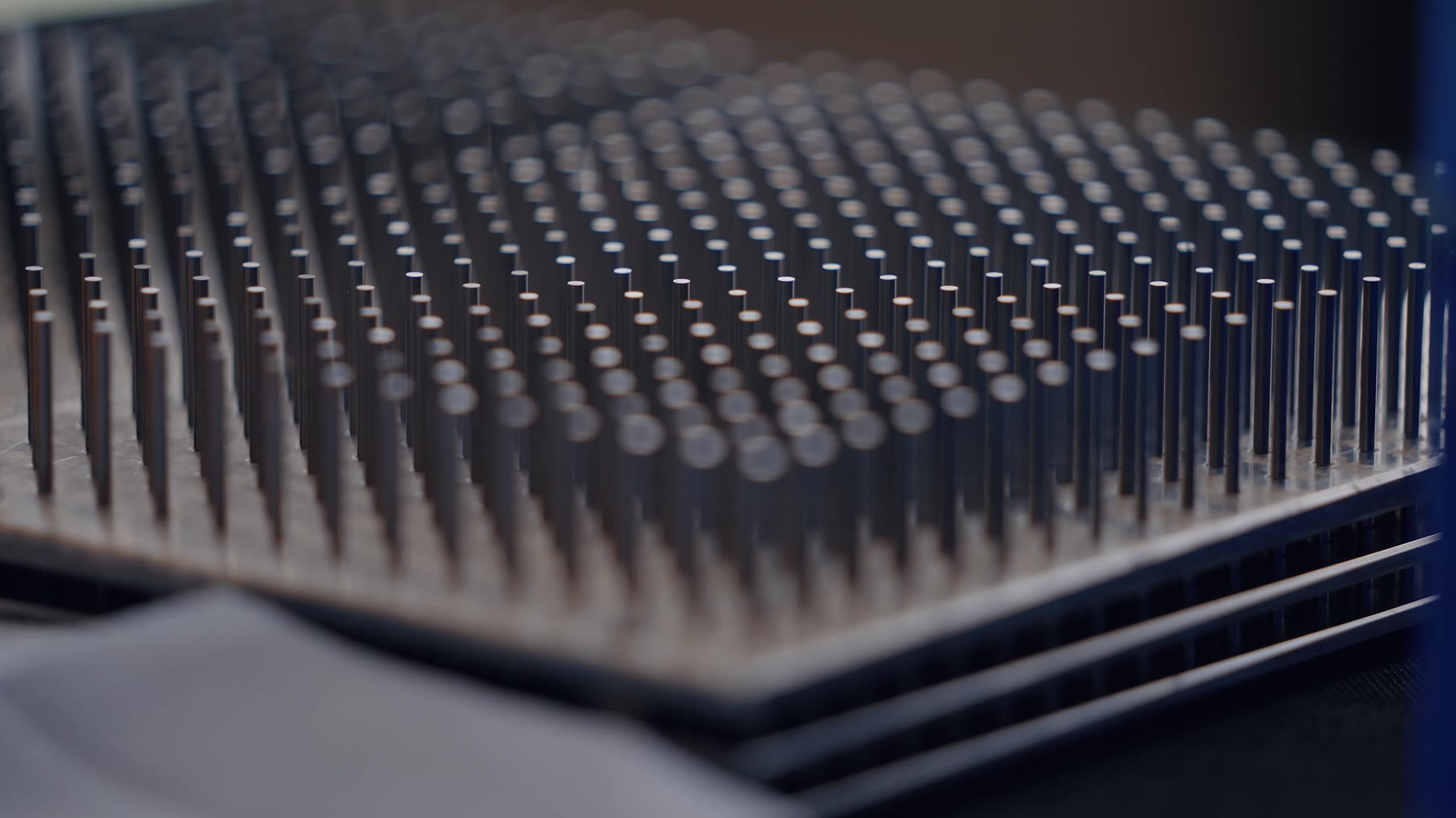 Centaines de pièces cylindriques dressées en damier sur un plateau d’atelier